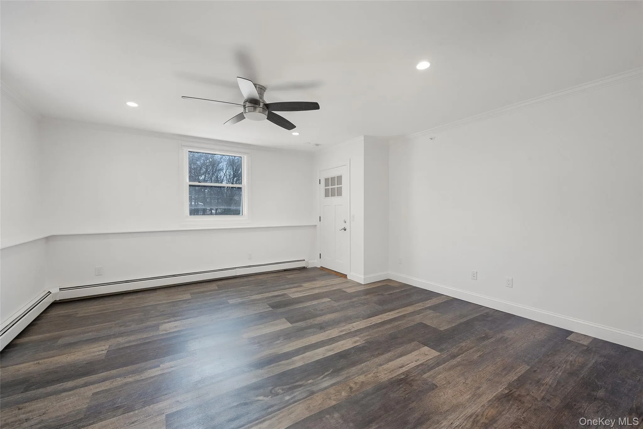 Spare room with ornamental molding, ceiling fan, a baseboard radiator, and dark hardwood / wood-style floors Spare room with ornamental molding, ceiling fan, a baseboard radiator, and dark hardwood / wood-style floors