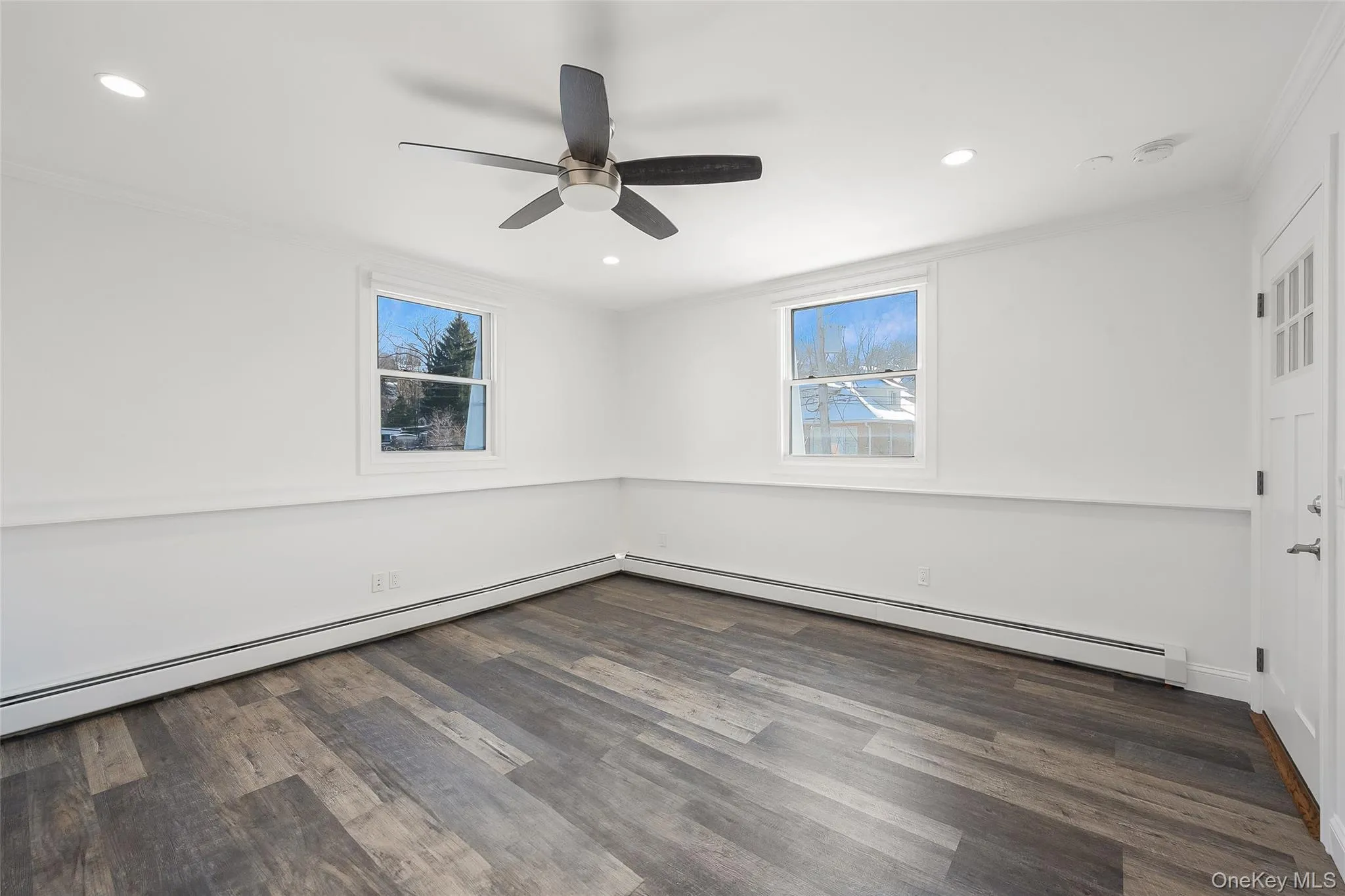 Spare room with ceiling fan, dark wood-type flooring, a baseboard heating unit, and ornamental molding Spare room with ceiling fan, dark wood-type flooring, a baseboard heating unit, and ornamental molding
