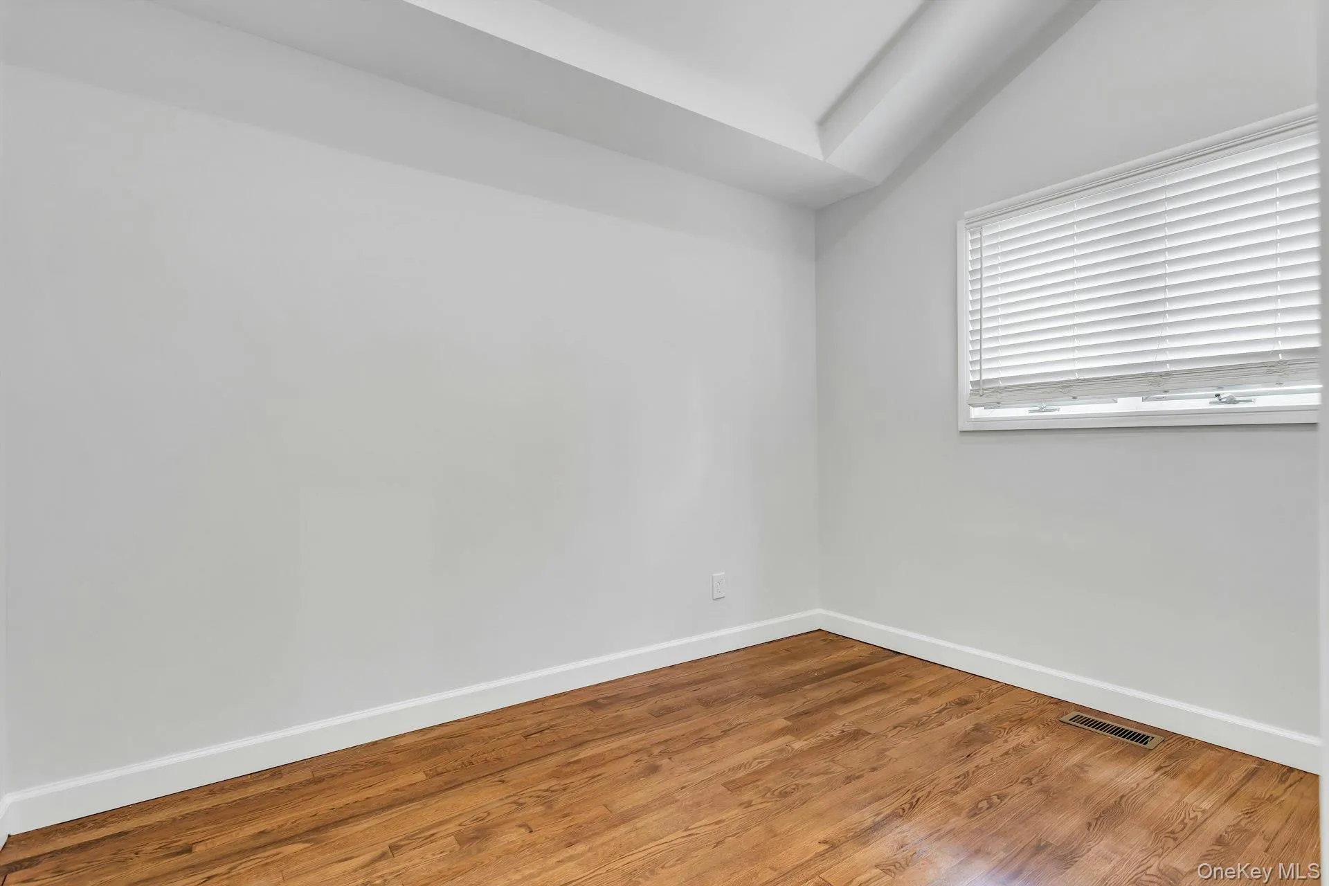Neutral wall paint, wood-finish flooring, white baseboards, and a window with blinds Neutral wall paint, wood-finish flooring, white baseboards, and a window with blinds