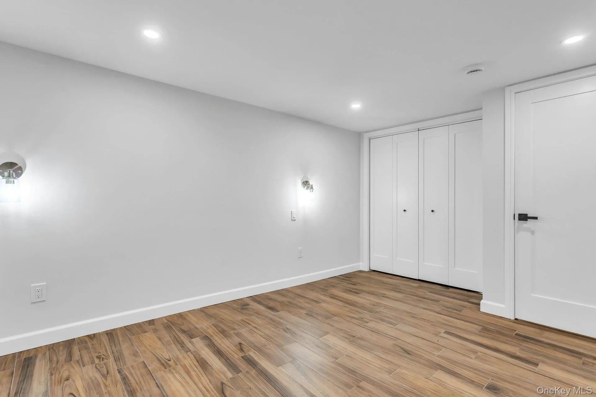 Wood-finish flooring throughout, bright recessed lighting, and modern wall sconces Wood-finish flooring throughout, bright recessed lighting, and modern wall sconces