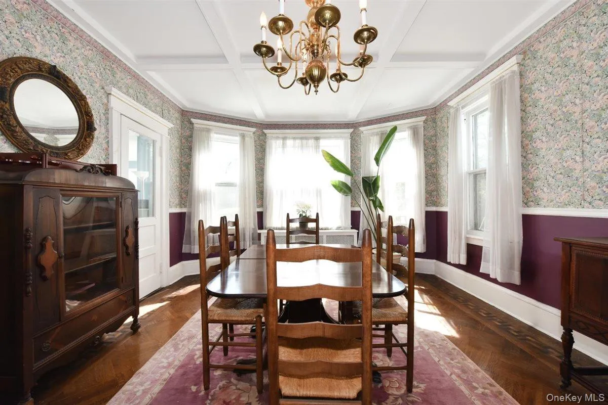Dining area with wallpapered walls, a chandelier, coffered ceiling, healthy amount of natural light, and a wainscoted wall Dining area with wallpapered walls, a chandelier, coffered ceiling, healthy amount of natural light, and a wainscoted wall