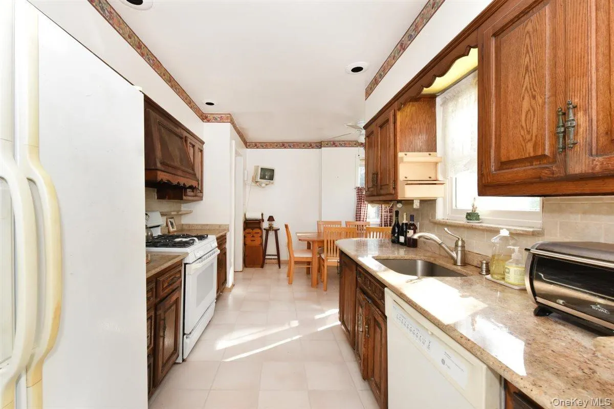 Kitchen featuring white appliances, decorative backsplash, light tile patterned floors, light stone counters, and custom exhaust hood Kitchen featuring white appliances, decorative backsplash, light tile patterned floors, light stone counters, and custom exhaust hood