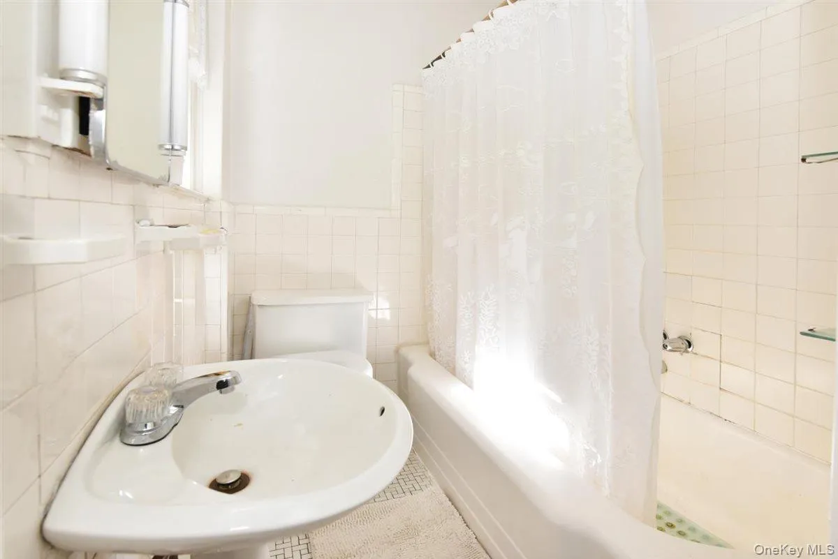 Bathroom with shower / bath combo with shower curtain and tile walls Bathroom with shower / bath combo with shower curtain and tile walls