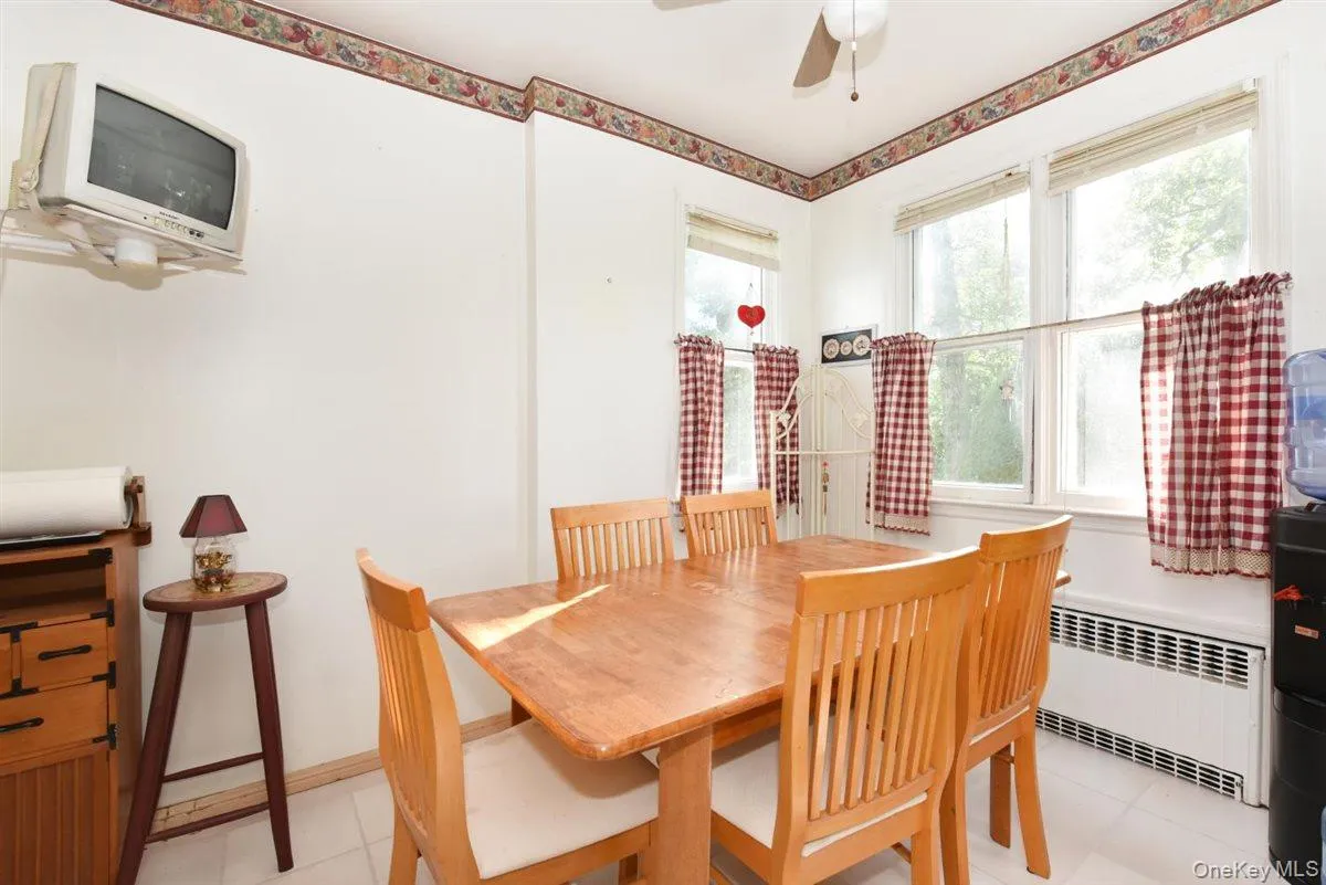 Dining space featuring radiator, light tile patterned floors, and a ceiling fan Dining space featuring radiator, light tile patterned floors, and a ceiling fan