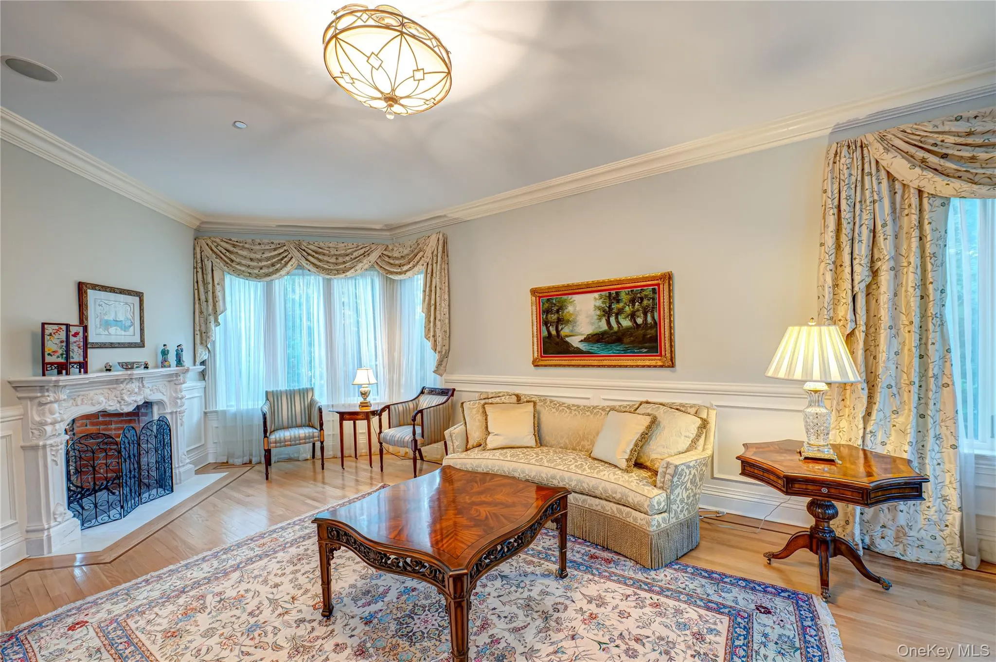Living room with crown molding, a fireplace with raised hearth, wainscoting, and wood finished floors Living room with crown molding, a fireplace with raised hearth, wainscoting, and wood finished floors