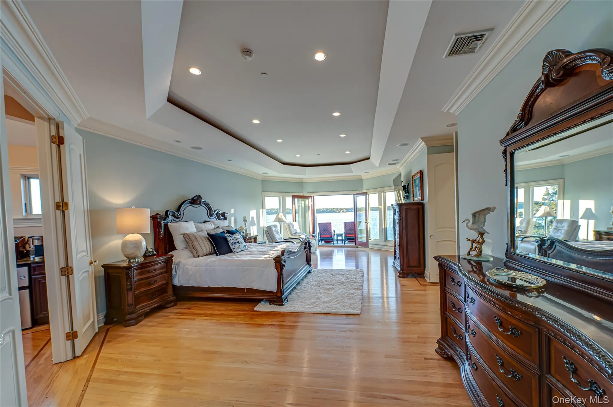Bedroom featuring crown molding, visible vents, light wood-type flooring, recessed lighting, and a tray ceiling Bedroom featuring crown molding, visible vents, light wood-type flooring, recessed lighting, and a tray ceiling