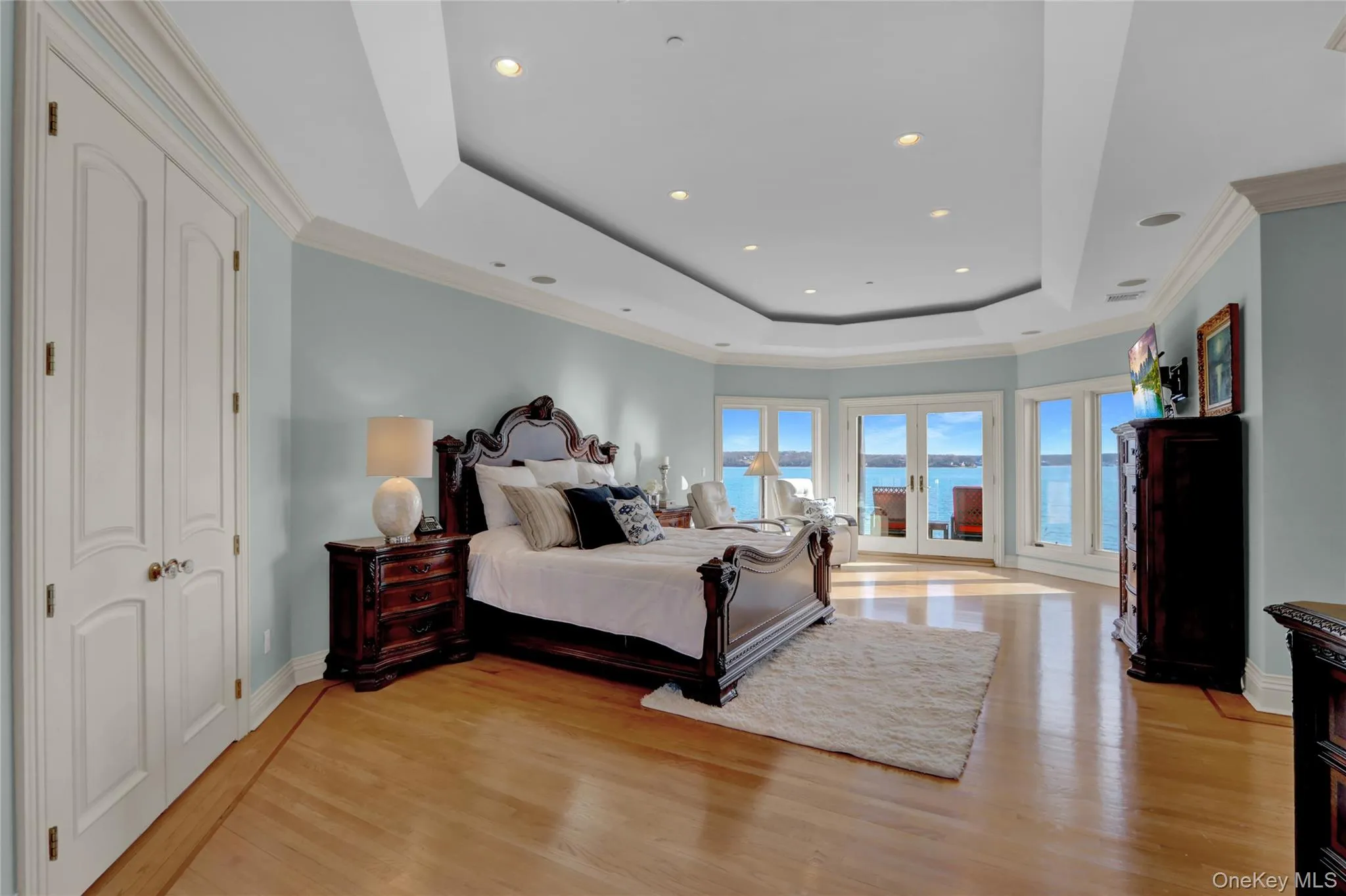 Bedroom with light wood-type flooring, recessed lighting, ornamental molding, and a tray ceiling Bedroom with light wood-type flooring, recessed lighting, ornamental molding, and a tray ceiling