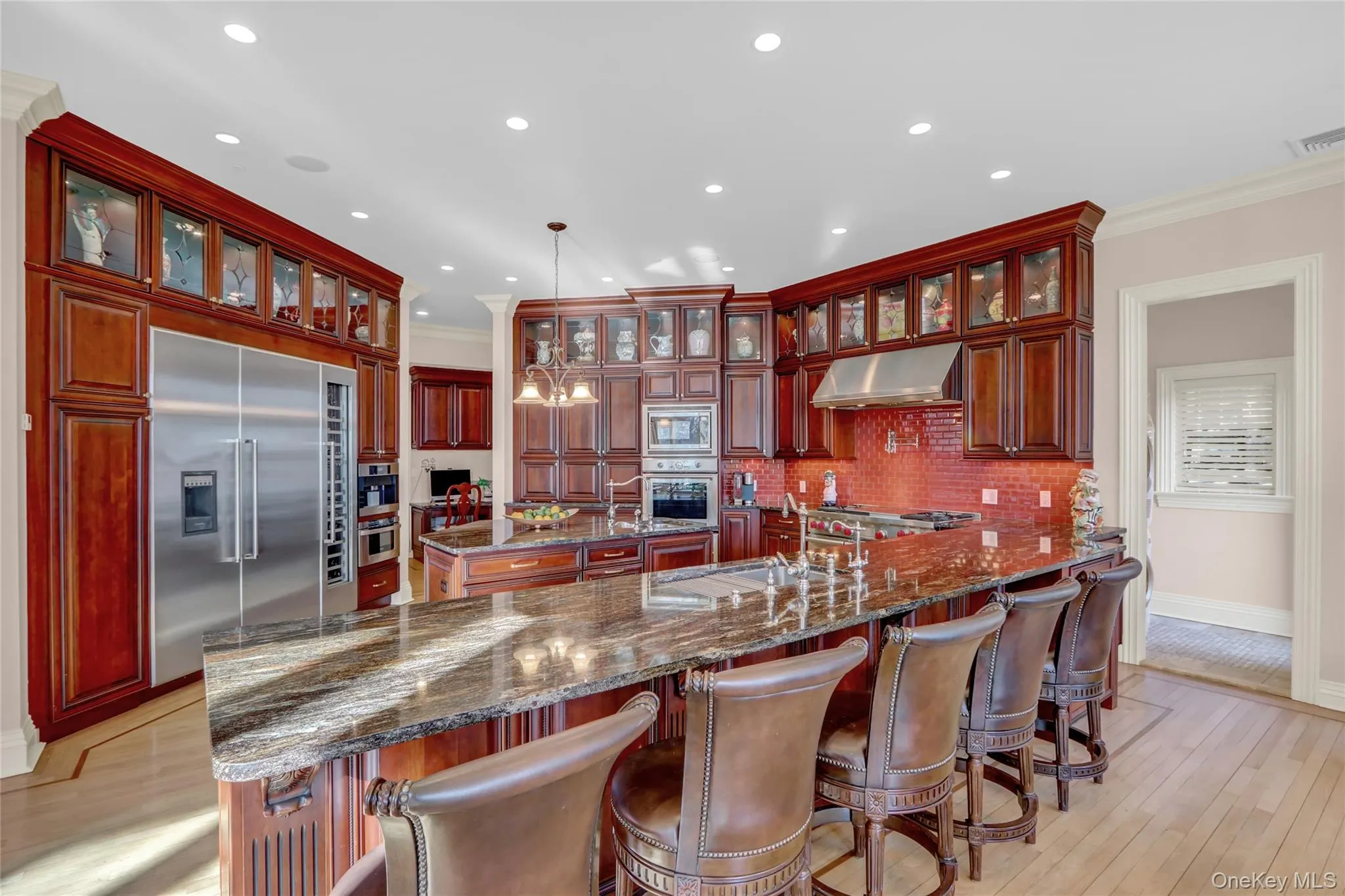 Kitchen featuring under cabinet range hood, built in appliances, dark brown cabinets, a sink, and a center island with sink Kitchen featuring under cabinet range hood, built in appliances, dark brown cabinets, a sink, and a center island with sink