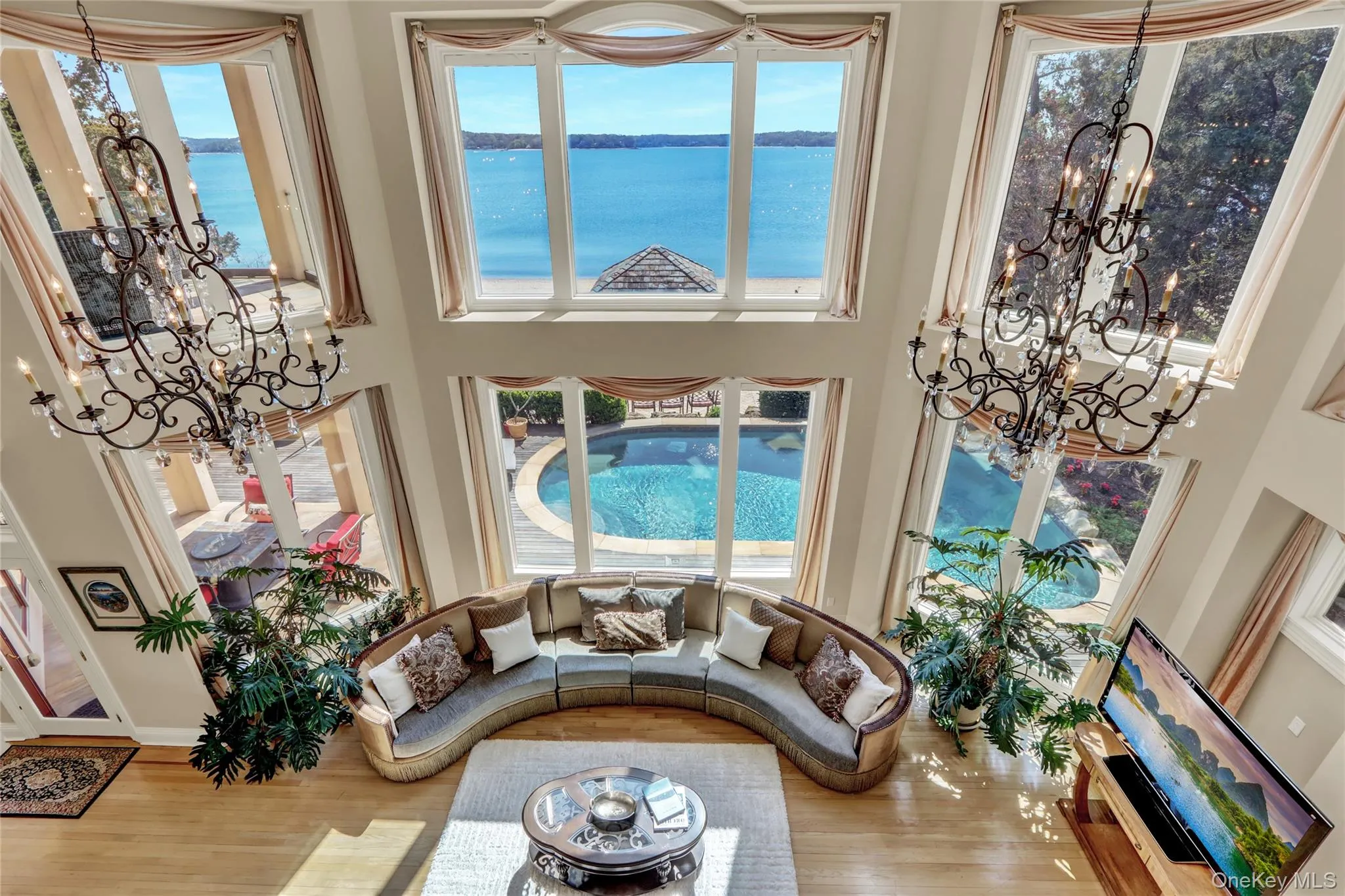 Living room with a high ceiling, wood finished floors, an inviting chandelier, and a water view Living room with a high ceiling, wood finished floors, an inviting chandelier, and a water view