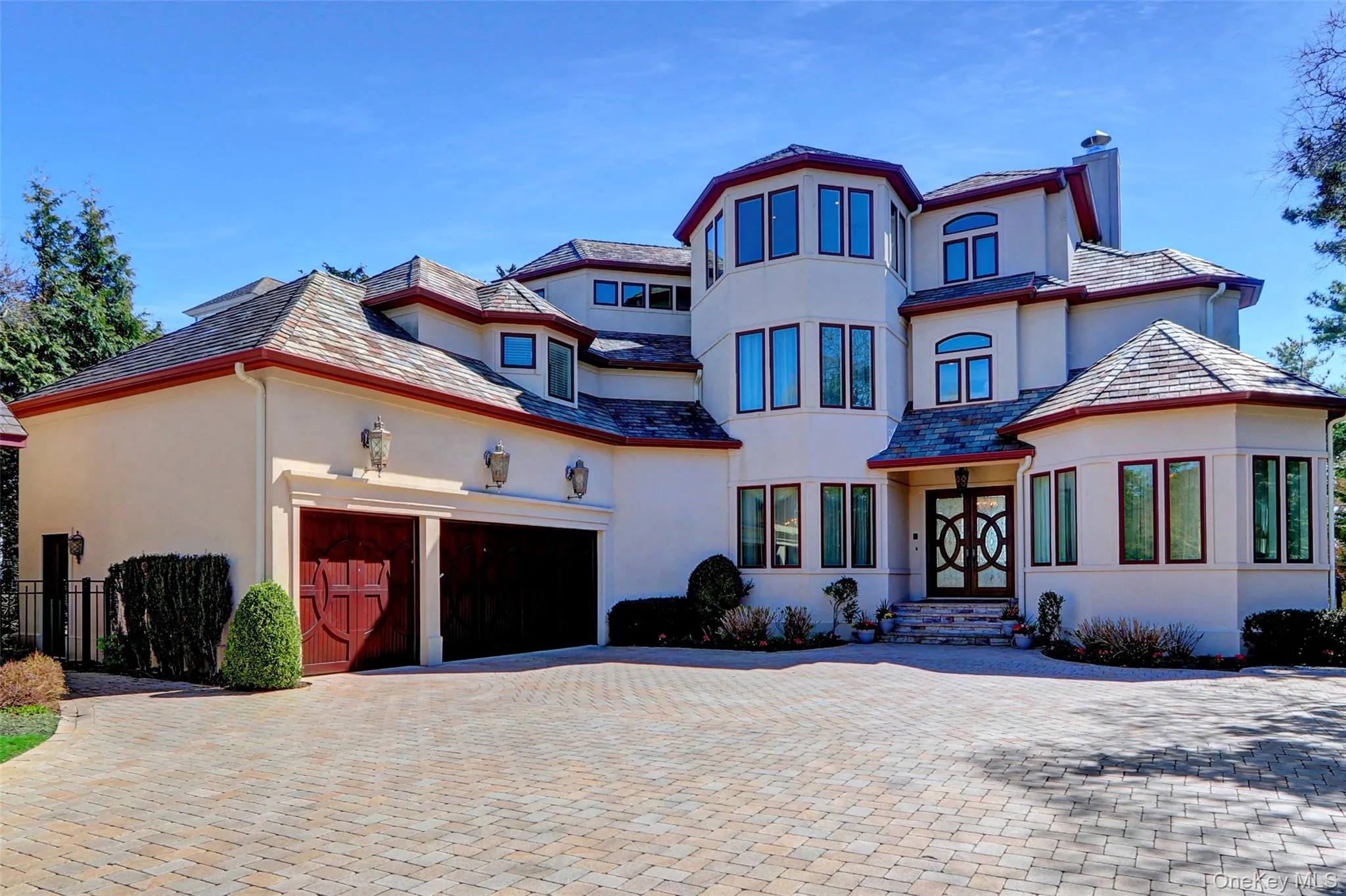 View of front of property with fence, a chimney, decorative driveway, an attached garage, and stucco siding View of front of property with fence, a chimney, decorative driveway, an attached garage, and stucco siding