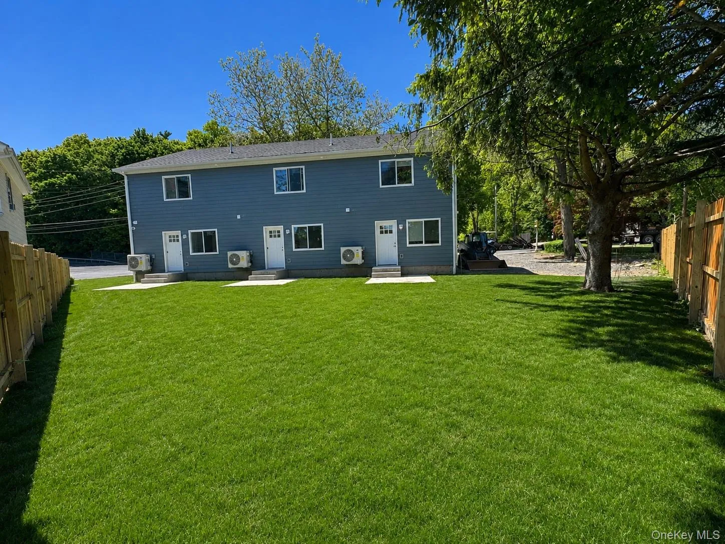 Expansive green lawn bordering a two-story residence with blue siding, white trim windows, and multiple entryways Expansive green lawn bordering a two-story residence with blue siding, white trim windows, and multiple entryways
