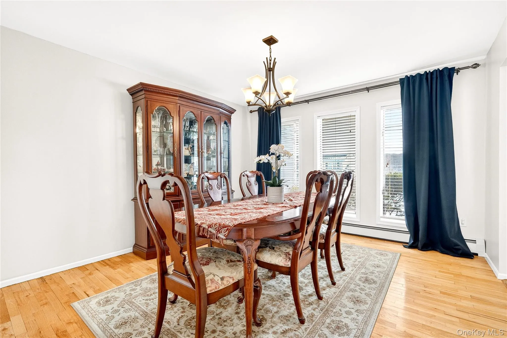 featuring a chandelier, light wood-style floors, and baseboard heating featuring a chandelier, light wood-style floors, and baseboard heating