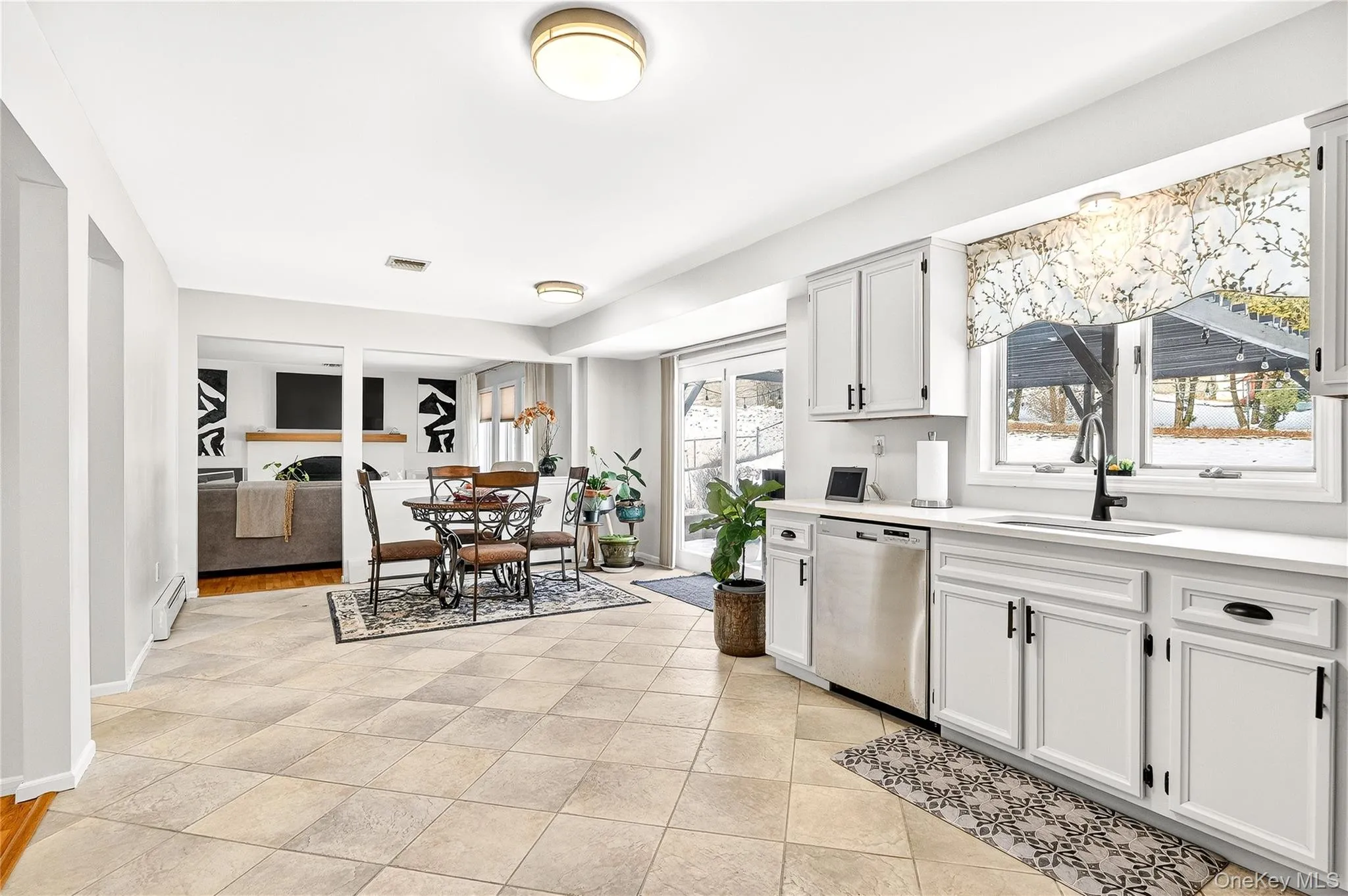 with stainless steel dishwasher, white cabinets, and baseboard heating with stainless steel dishwasher, white cabinets, and baseboard heating