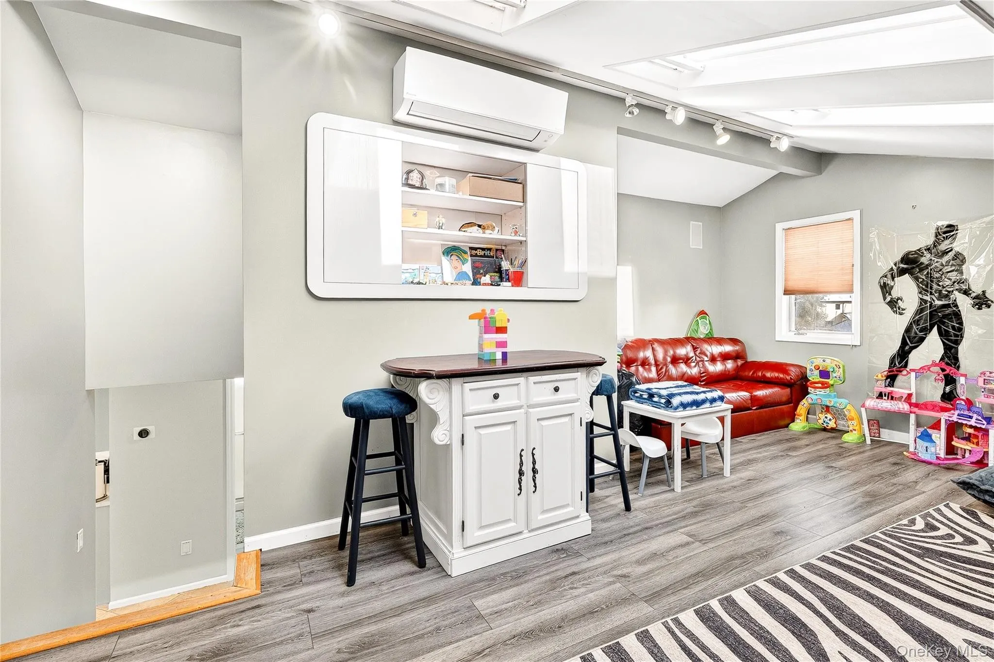 Rec room featuring rail lighting, a wall mounted AC, light wood-type flooring, and lofted ceiling Rec room featuring rail lighting, a wall mounted AC, light wood-type flooring, and lofted ceiling