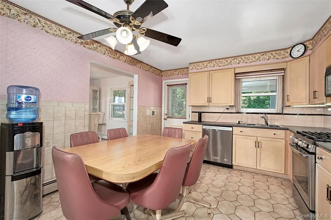 Kitchen with light brown cabinets, light tile patterned floors, ceiling fan, stainless steel appliances, and a baseboard radiator Kitchen with light brown cabinets, light tile patterned floors, ceiling fan, stainless steel appliances, and a baseboard radiator
