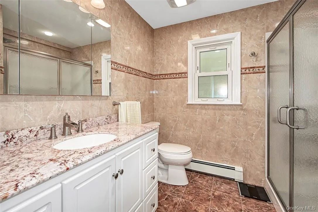Bathroom featuring tile walls, a baseboard heating unit, and vanity Bathroom featuring tile walls, a baseboard heating unit, and vanity