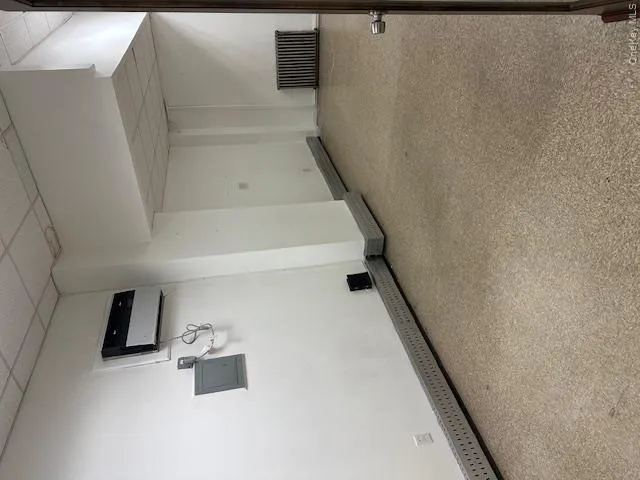 Below grade area with a paneled ceiling, radiator heating unit, electric panel, and a wall unit AC Below grade area with a paneled ceiling, radiator heating unit, electric panel, and a wall unit AC