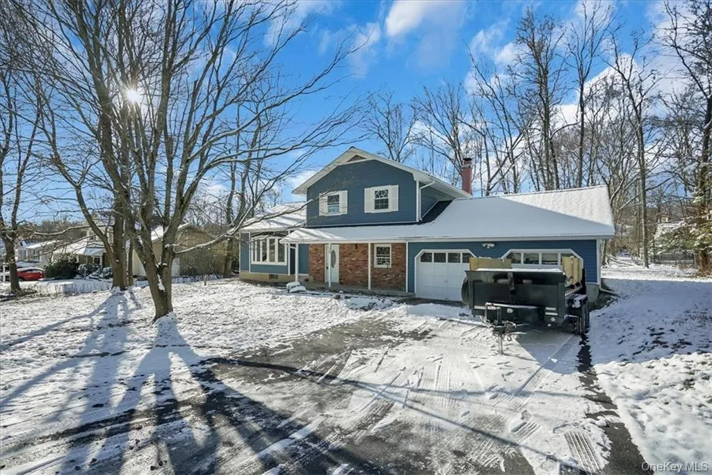 Traditional home with an attached garage, brick siding, and a chimney Traditional home with an attached garage, brick siding, and a chimney