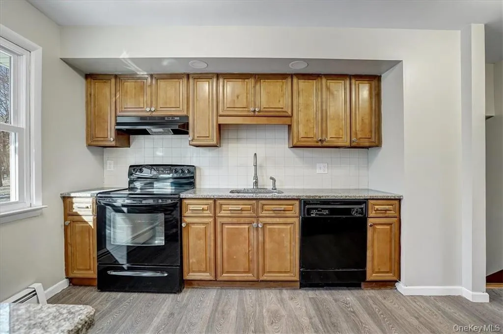 Kitchen with black appliances, brown cabinetry, and decorative backsplash Kitchen with black appliances, brown cabinetry, and decorative backsplash