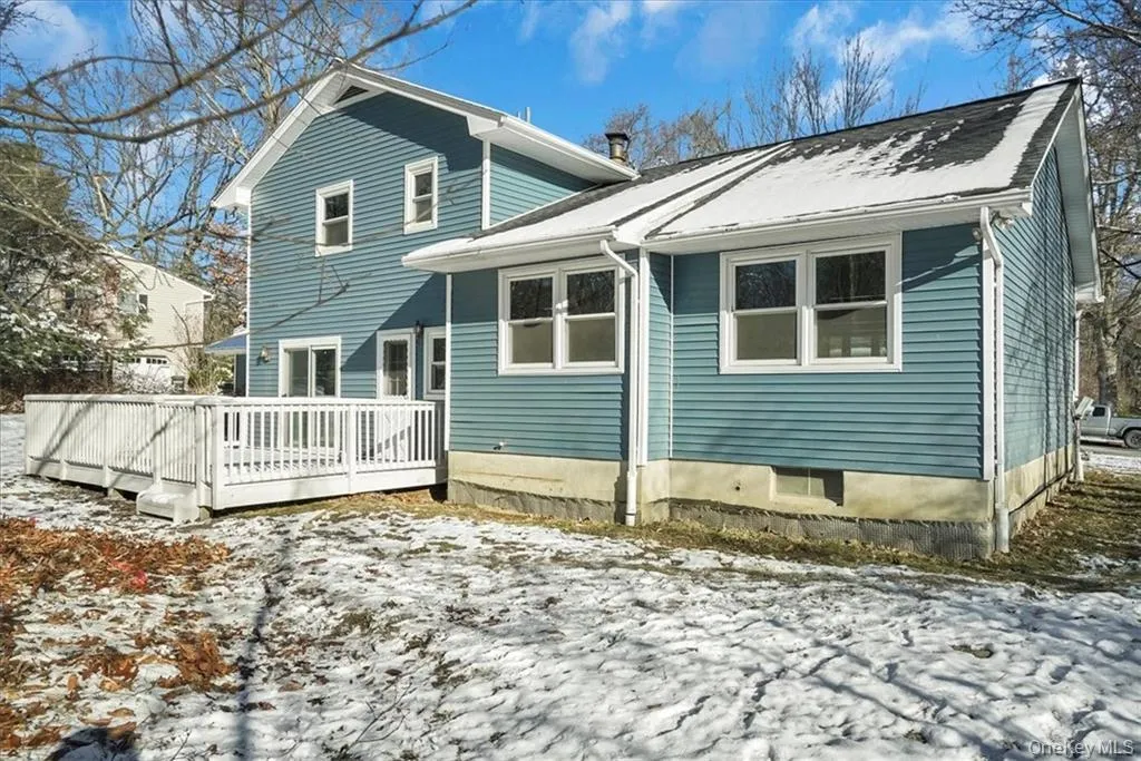 Snow covered back of property with a wooden deck Snow covered back of property with a wooden deck