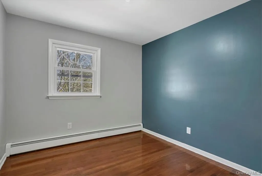 Empty room featuring a baseboard radiator and dark wood-style floors Empty room featuring a baseboard radiator and dark wood-style floors