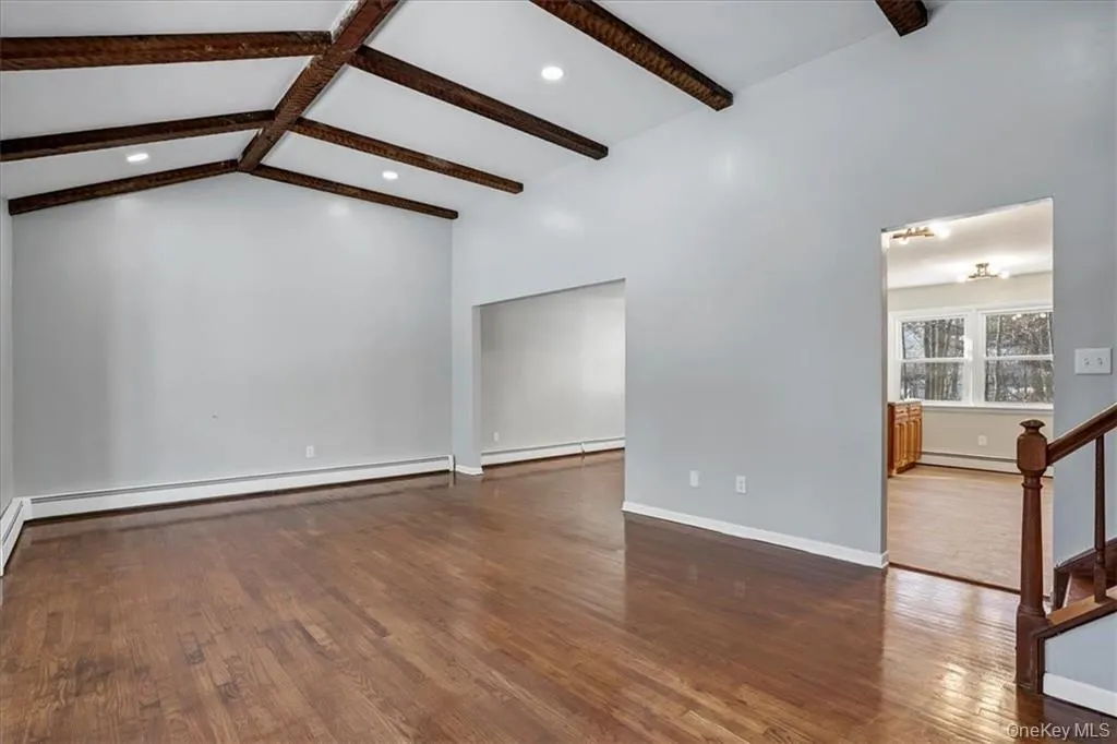 Spare room with dark wood-type flooring, stairway, a baseboard radiator, baseboard heating, and recessed lighting Spare room with dark wood-type flooring, stairway, a baseboard radiator, baseboard heating, and recessed lighting
