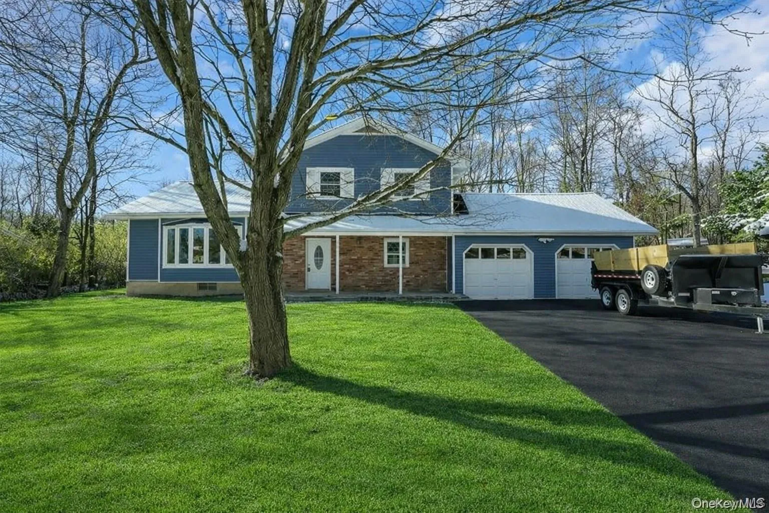 View of front of property with a garage, a front lawn, driveway, and brick siding View of front of property with a garage, a front lawn, driveway, and brick siding