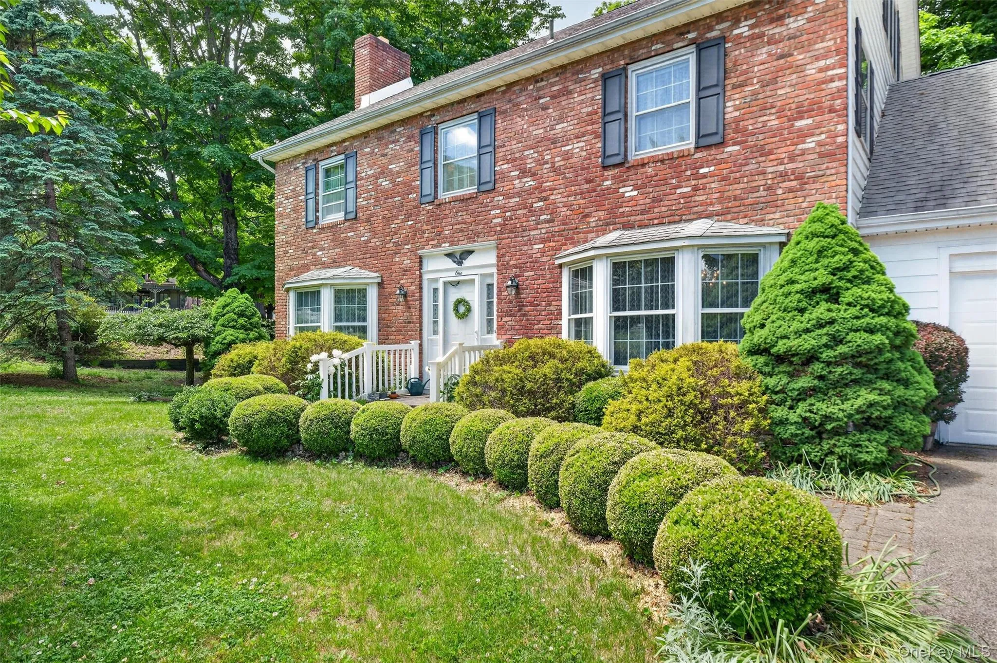 1 Taft - Welcome to Cornwall on Hudson - Brick exterior featuring a white entry door with side lights, multiple bay windows, and dark shutters 1 Taft - Welcome to Cornwall on Hudson - Brick exterior featuring a white entry door with side lights, multiple bay windows, and dark shutters