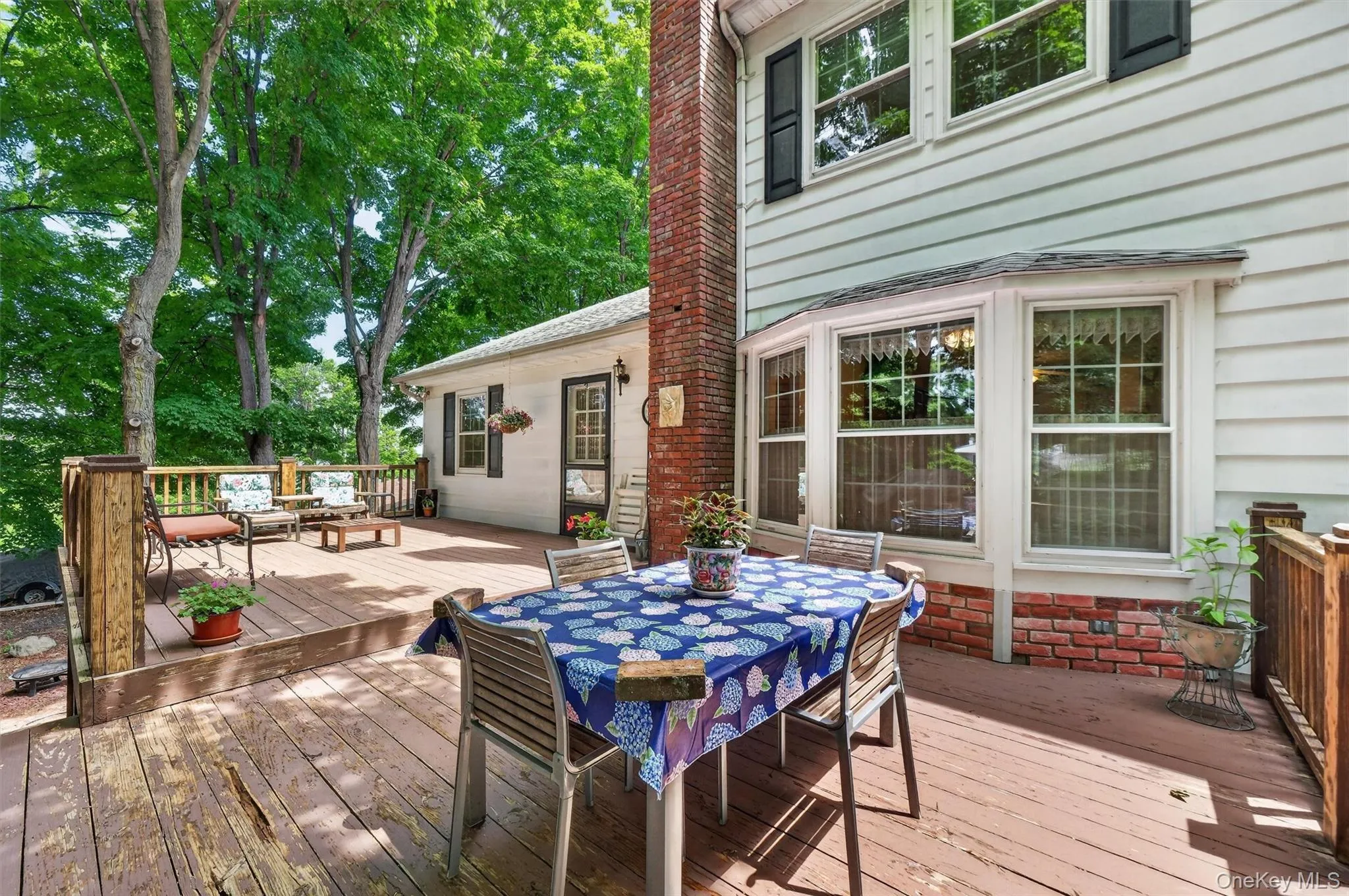 The expansive multi-level wood deck features wood railings and a mature tree canopy. The expansive multi-level wood deck features wood railings and a mature tree canopy.