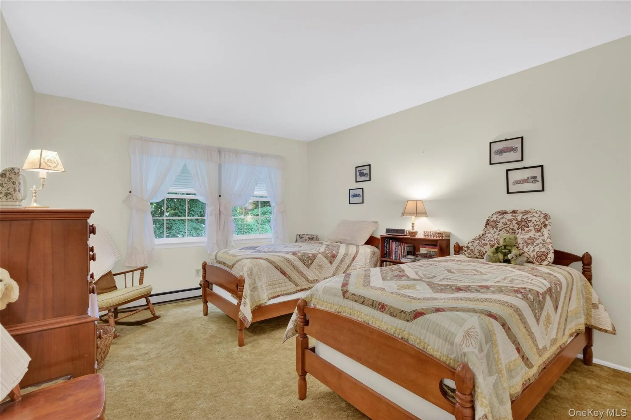 Carpeted room featuring light-toned walls, two windows with white blinds, and baseboard heating Carpeted room featuring light-toned walls, two windows with white blinds, and baseboard heating