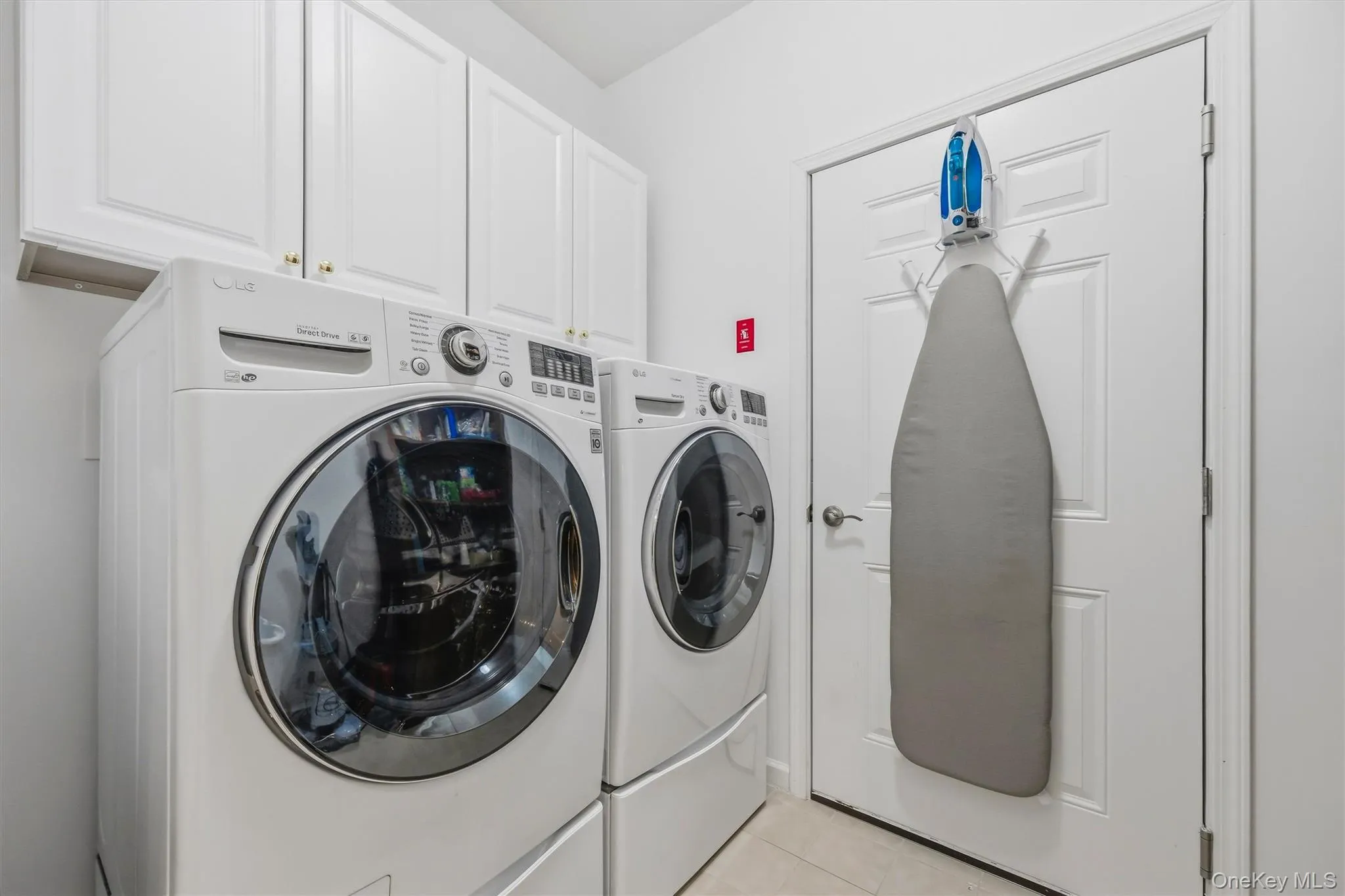 Well-equipped laundry room with front-loading LG washer and dryer on pedestals, ample cabinet storage and a floor drain for added peace of mind. Well-equipped laundry room with front-loading LG washer and dryer on pedestals, ample cabinet storage and a floor drain for added peace of mind.