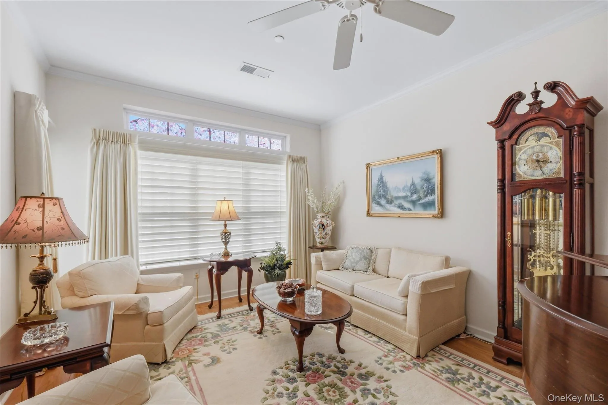 Living room featuring hardwood floors, crown molding, and a ceiling fan for year-round comfort. Living room featuring hardwood floors, crown molding, and a ceiling fan for year-round comfort.