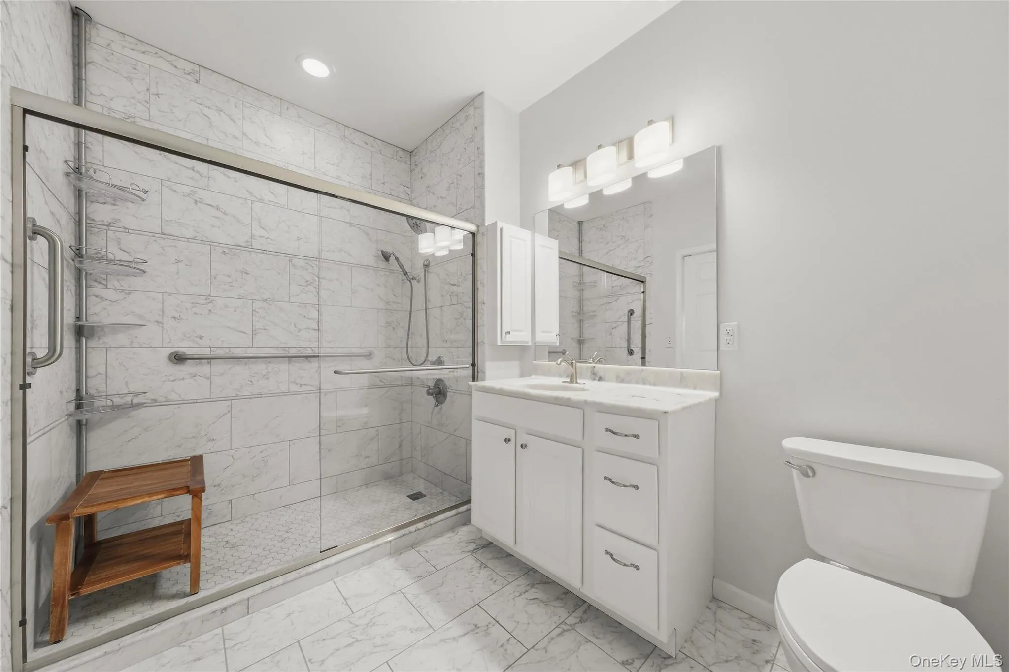 Renovated primary bathroom featuring marble tile and a walk-in shower stall. Renovated primary bathroom featuring marble tile and a walk-in shower stall.