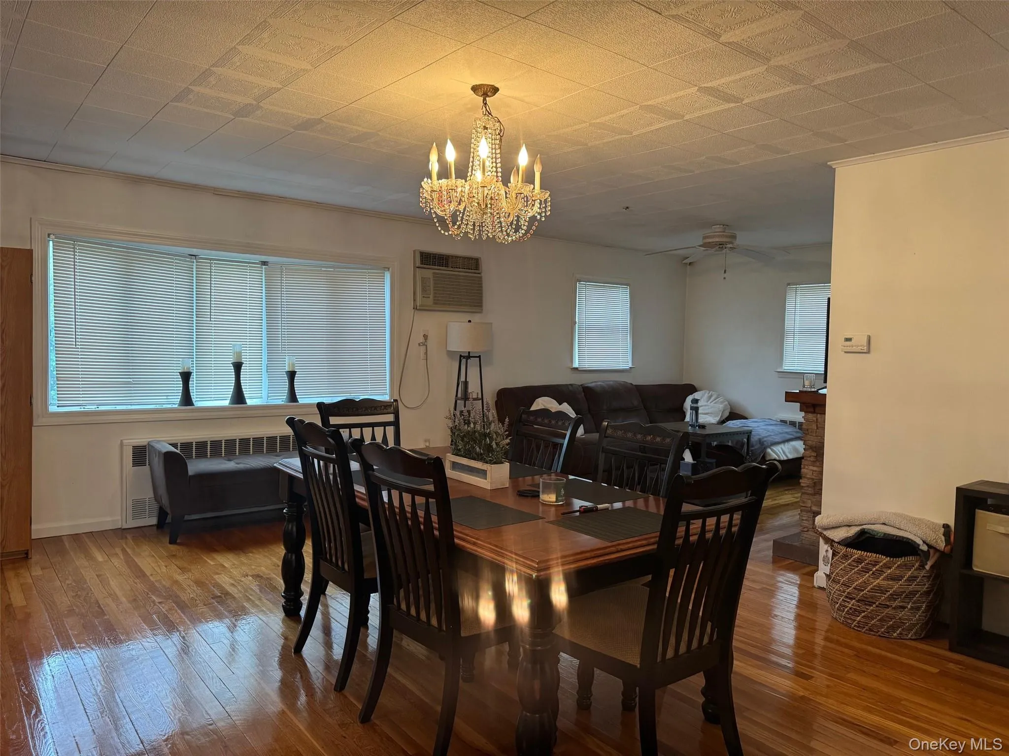 Dining space featuring a chandelier, wood-type flooring, a wall mounted AC, and a ceiling fan Dining space featuring a chandelier, wood-type flooring, a wall mounted AC, and a ceiling fan