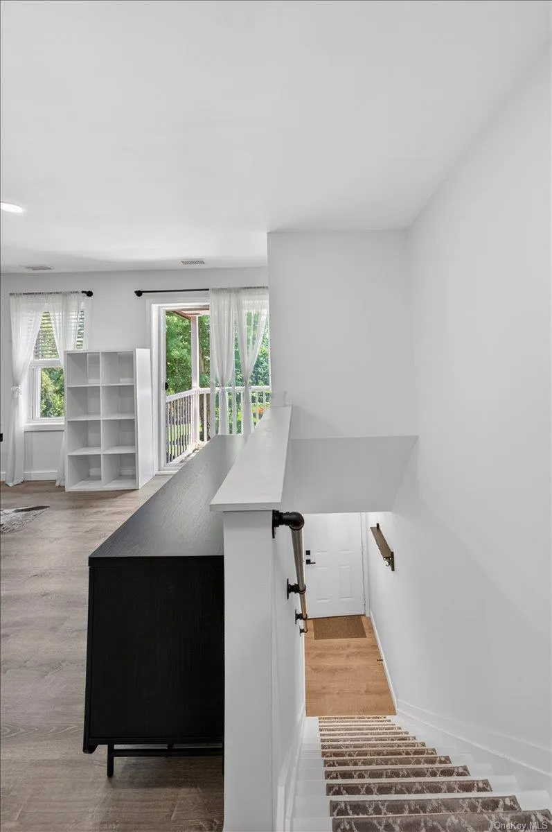 Staircase featuring a patterned runner leading to a lower level with wood-finish flooring Staircase featuring a patterned runner leading to a lower level with wood-finish flooring