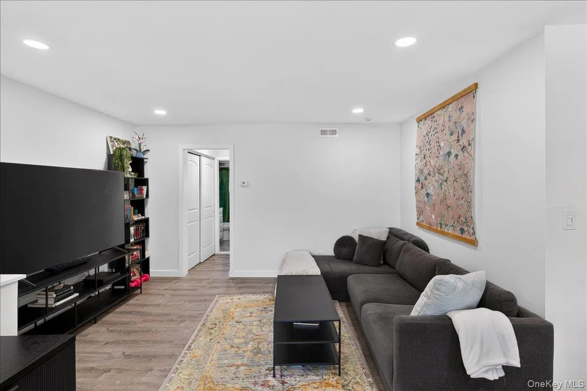 Recessed lighting illuminates this living space featuring light-colored walls and wood-finish flooring Recessed lighting illuminates this living space featuring light-colored walls and wood-finish flooring