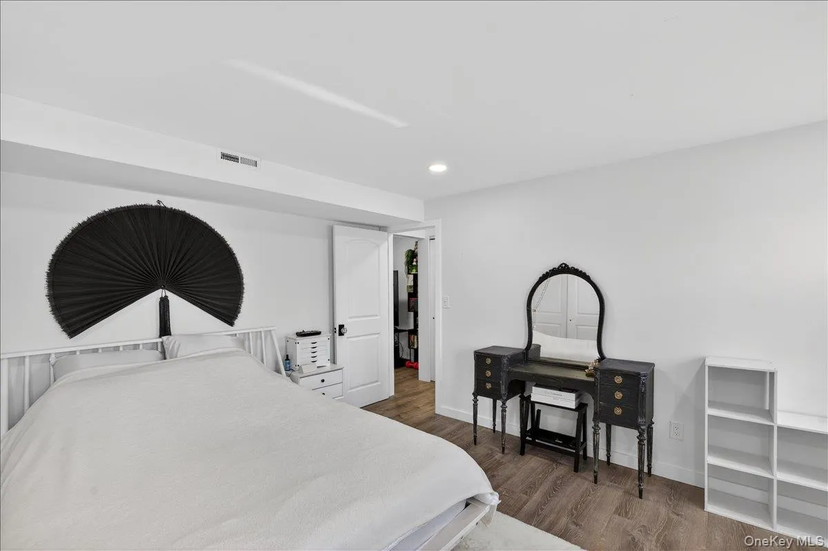 Bedroom featuring wood-finish flooring, recessed lighting, white walls, and a white interior door Bedroom featuring wood-finish flooring, recessed lighting, white walls, and a white interior door