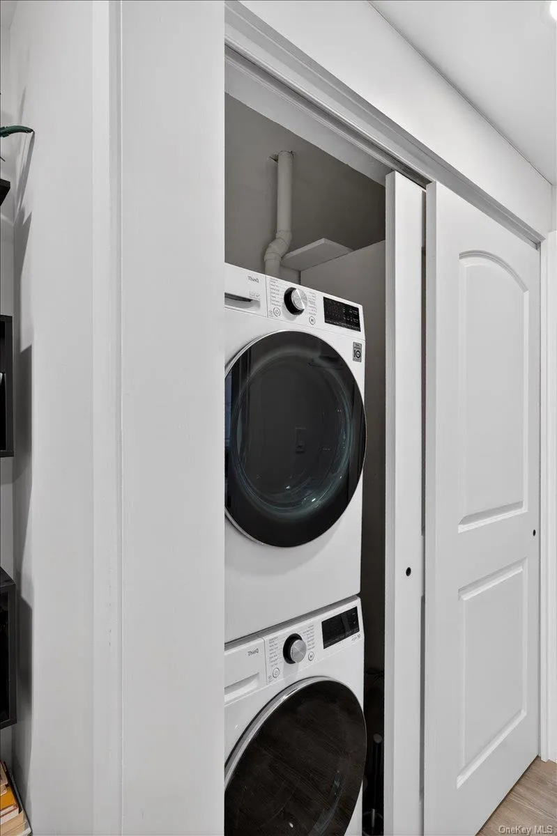 Laundry closet with a stacked washer and dryer, featuring white panel doors with an arched top design Laundry closet with a stacked washer and dryer, featuring white panel doors with an arched top design