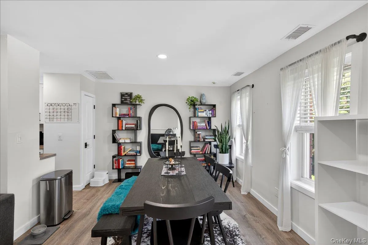 Open-concept dining area featuring wood-finish flooring, recessed lighting, and multiple windows with white blinds Open-concept dining area featuring wood-finish flooring, recessed lighting, and multiple windows with white blinds