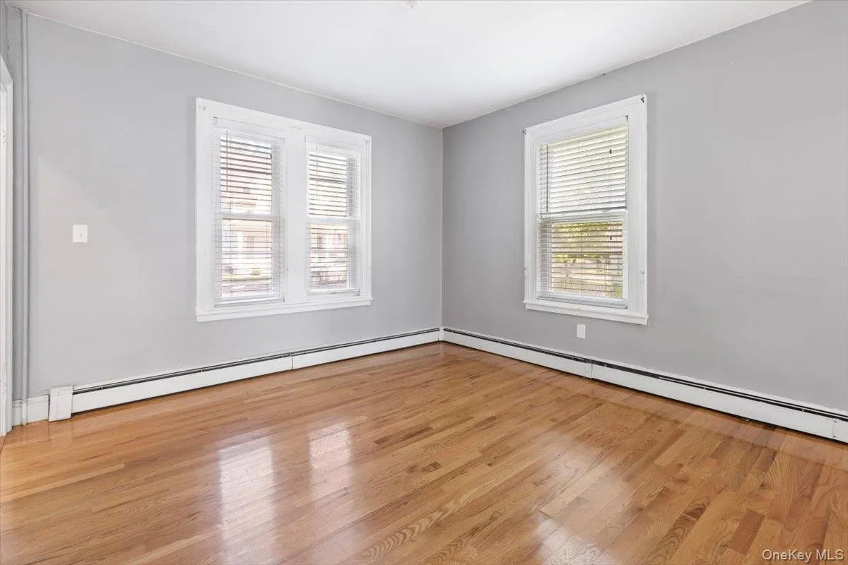 Unfurnished room featuring wood finished floors and a baseboard radiator Unfurnished room featuring wood finished floors and a baseboard radiator