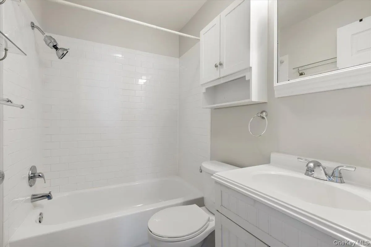 Full bathroom featuring washtub / shower combination, toilet, and vanity Full bathroom featuring washtub / shower combination, toilet, and vanity
