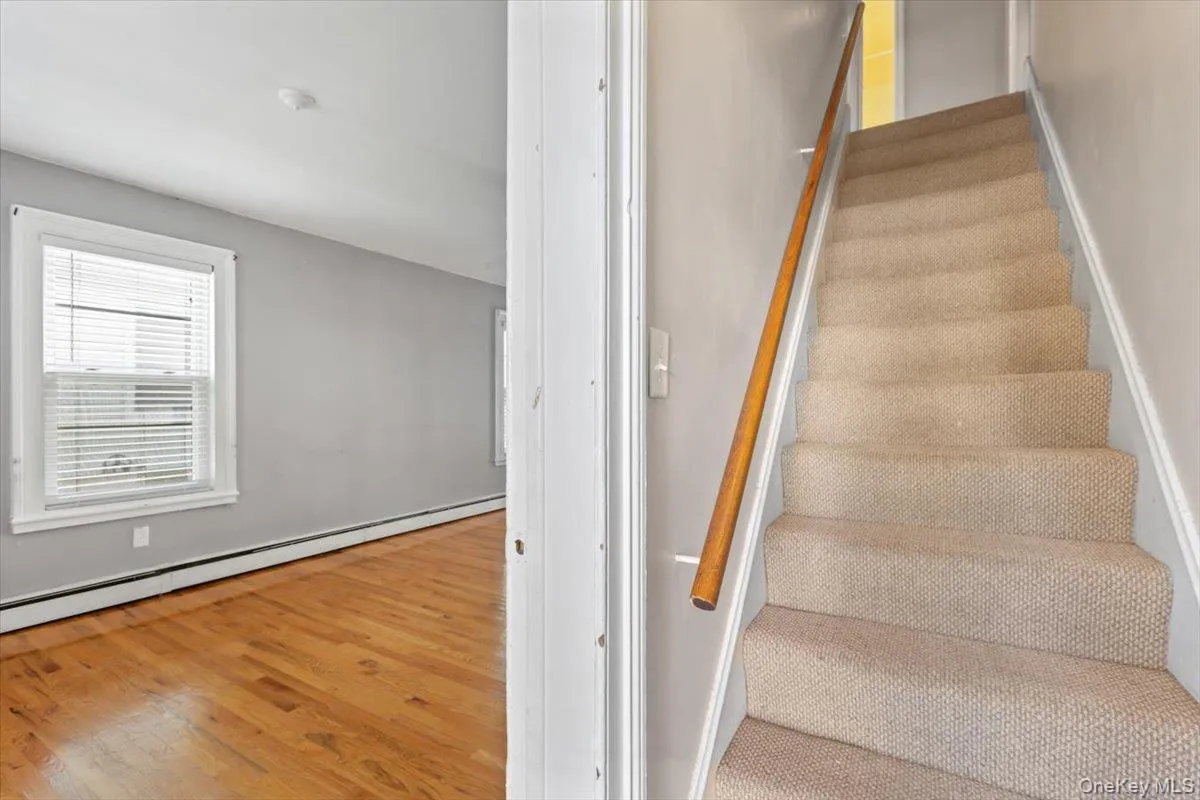 Stairs featuring wood finished floors and baseboard heating Stairs featuring wood finished floors and baseboard heating