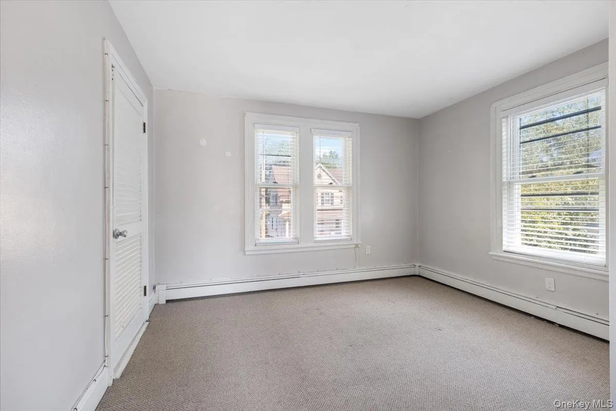 Carpeted spare room with baseboard heating and a healthy amount of sunlight Carpeted spare room with baseboard heating and a healthy amount of sunlight