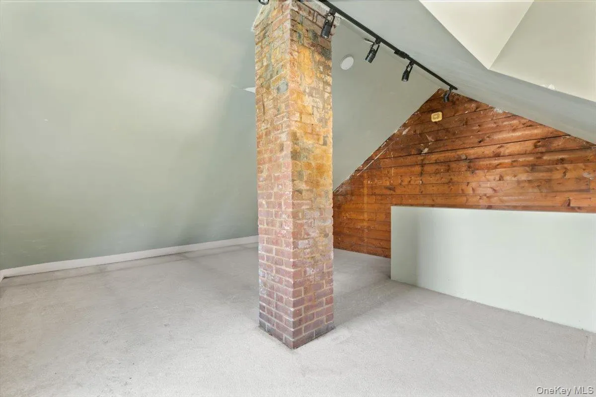 Bonus room with wooden walls, decorative columns, vaulted ceiling, and a barn door Bonus room with wooden walls, decorative columns, vaulted ceiling, and a barn door