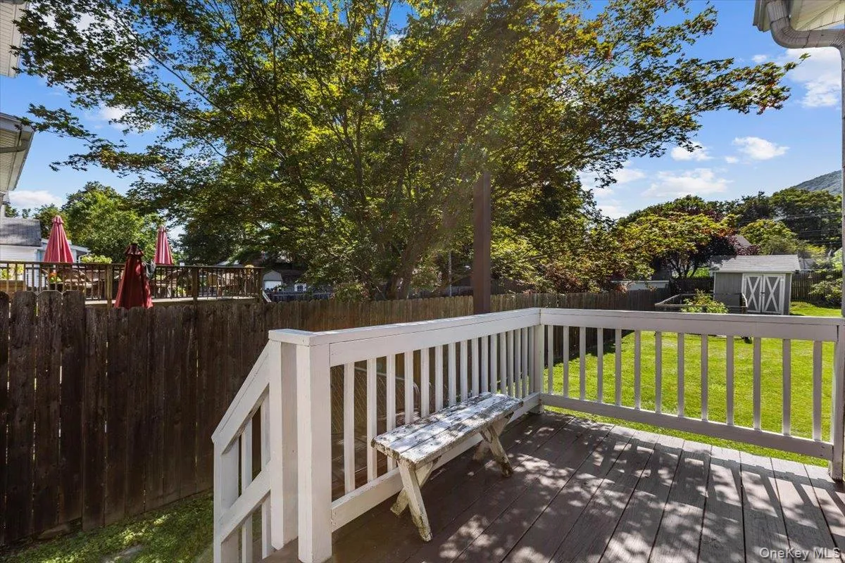 Wooden terrace with an outdoor structure, a storage shed, a lawn, and a fenced backyard Wooden terrace with an outdoor structure, a storage shed, a lawn, and a fenced backyard