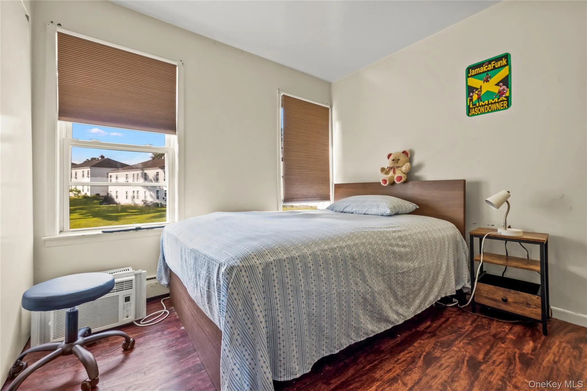 Bedroom with dark wood finished floors, a baseboard radiator, and a wall mounted AC Bedroom with dark wood finished floors, a baseboard radiator, and a wall mounted AC