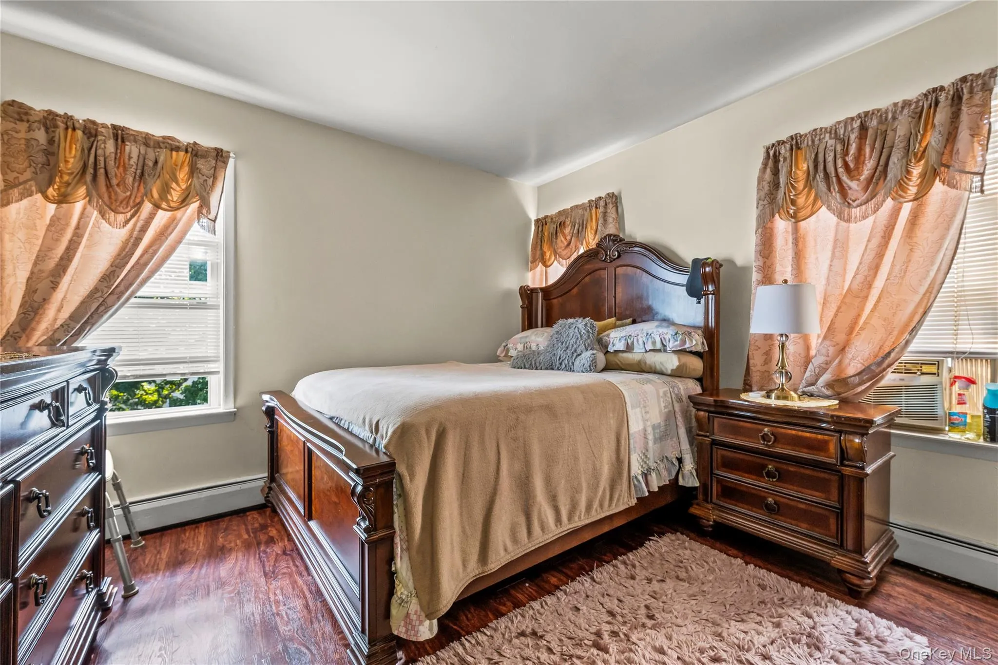 Bedroom featuring baseboard heating and dark wood-style floors Bedroom featuring baseboard heating and dark wood-style floors