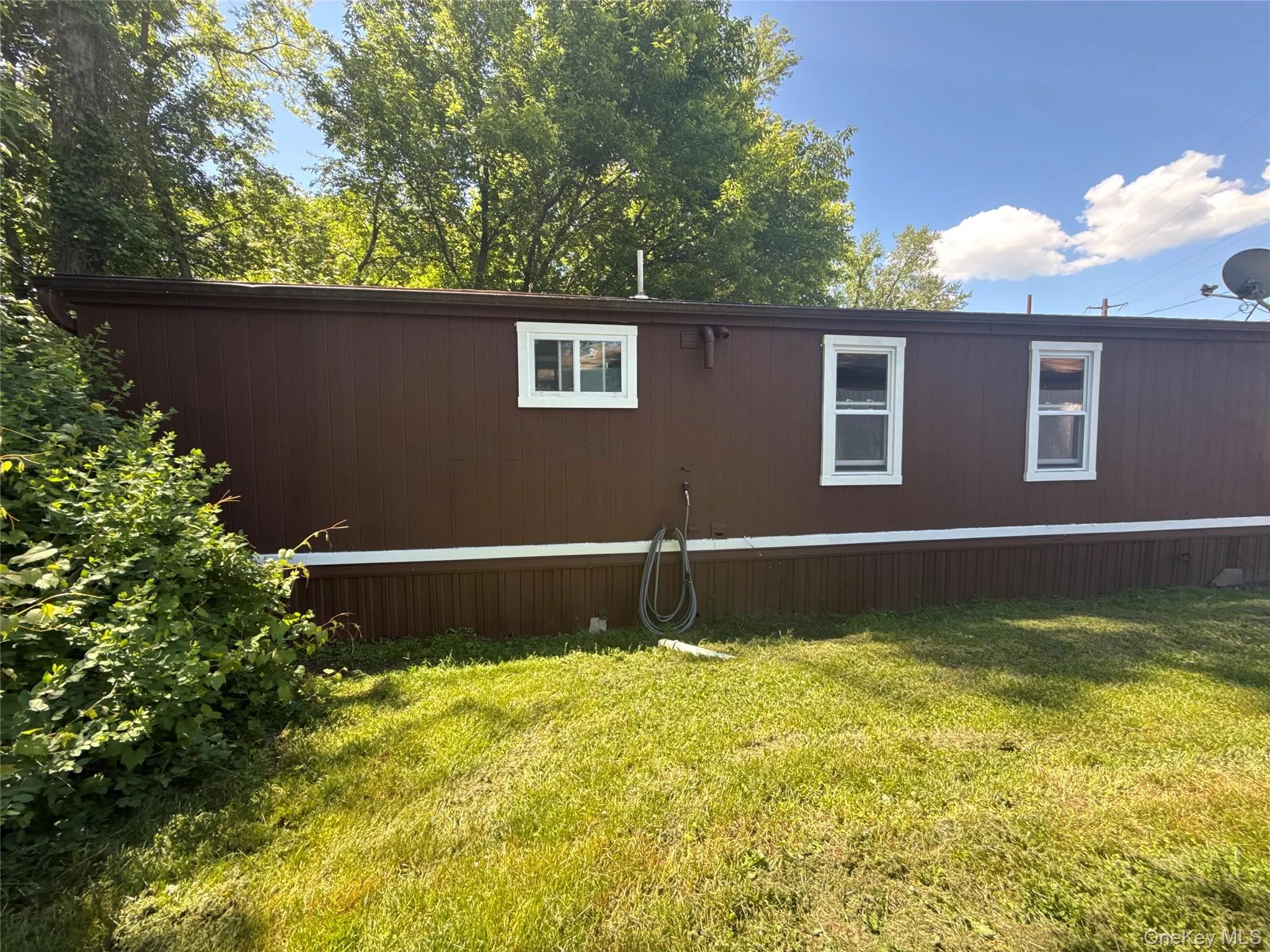 Brown vertical siding with white trim and white-framed windows Brown vertical siding with white trim and white-framed windows