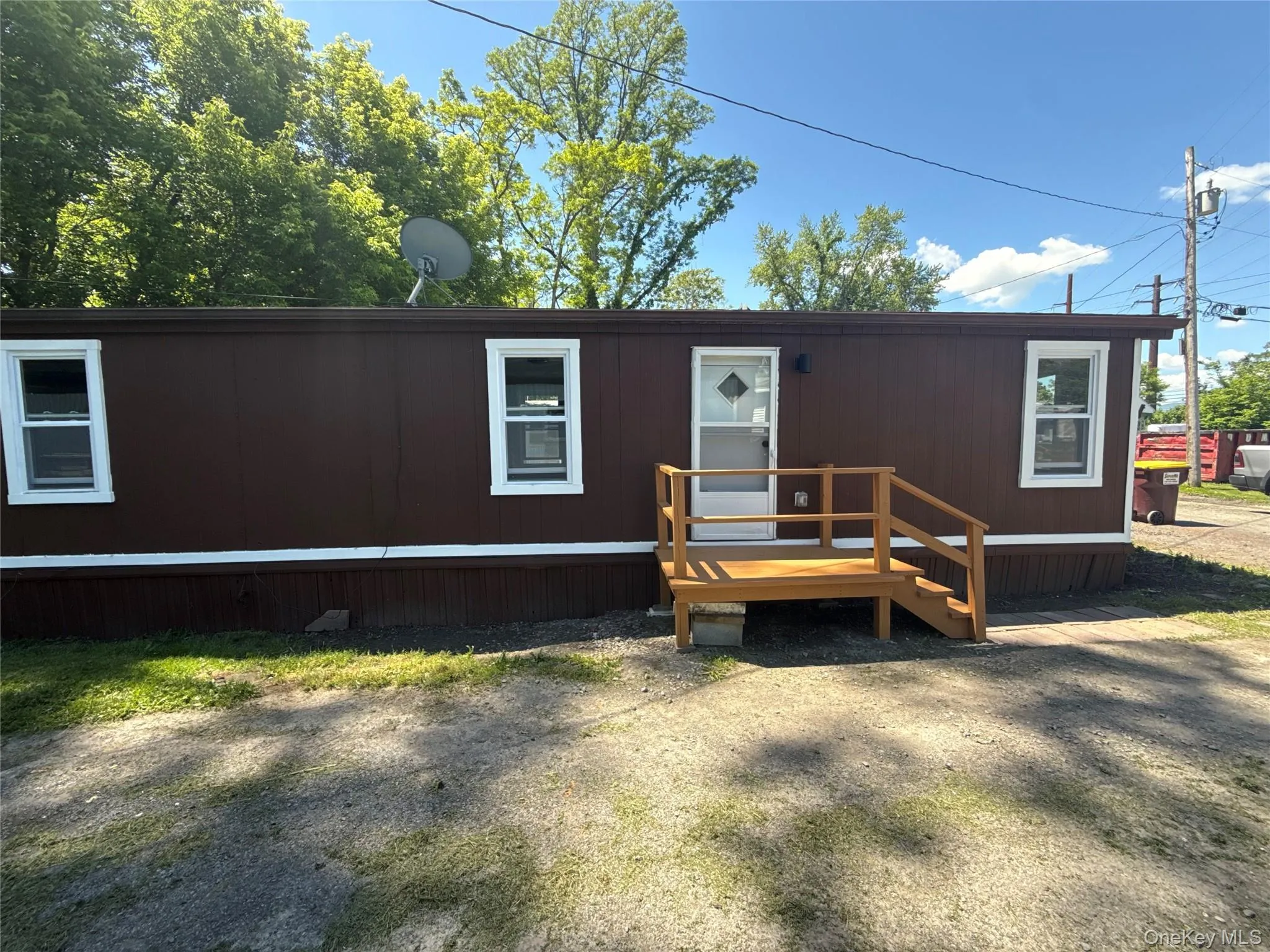 Brown mobile home exterior with white trim windows and a light wood-finish entry deck Brown mobile home exterior with white trim windows and a light wood-finish entry deck