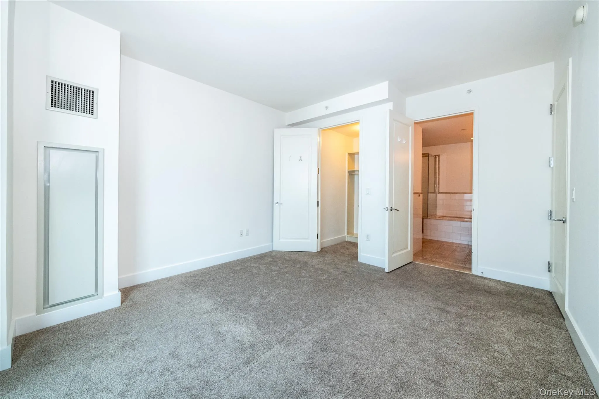 Primary bedroom with carpet flooring, a spacious walk in closet, and ensuite bath Primary bedroom with carpet flooring, a spacious walk in closet, and ensuite bath